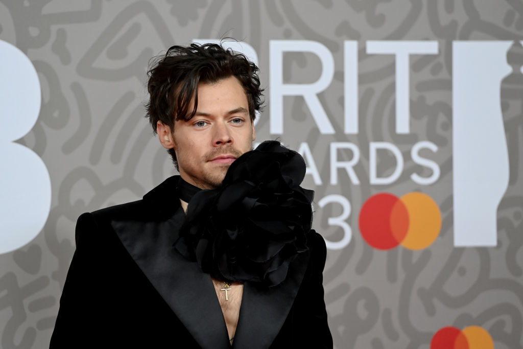 Harry Styles poses in a velvet blazer with a large floral neckline at the BRIT Awards