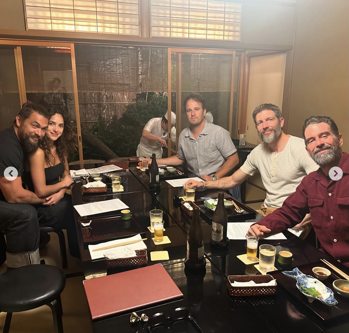 Jason, Adria, and friends sit together at a dining table with food and drinks