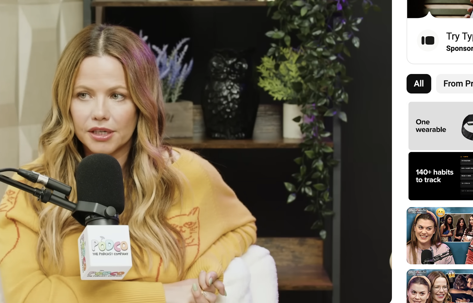 Sasha Pieterse speaking into a microphone during an interview on Pretty Little Liars: True Crime. She is wearing a patterned long-sleeve sweater