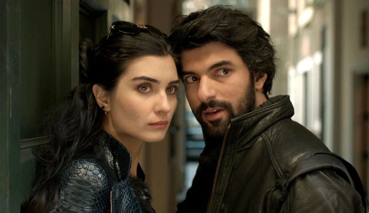 Persona de cabello oscuro y chaqueta de cuero habla con una mujer de cabello largo y suelto que lleva una chaqueta texturizada