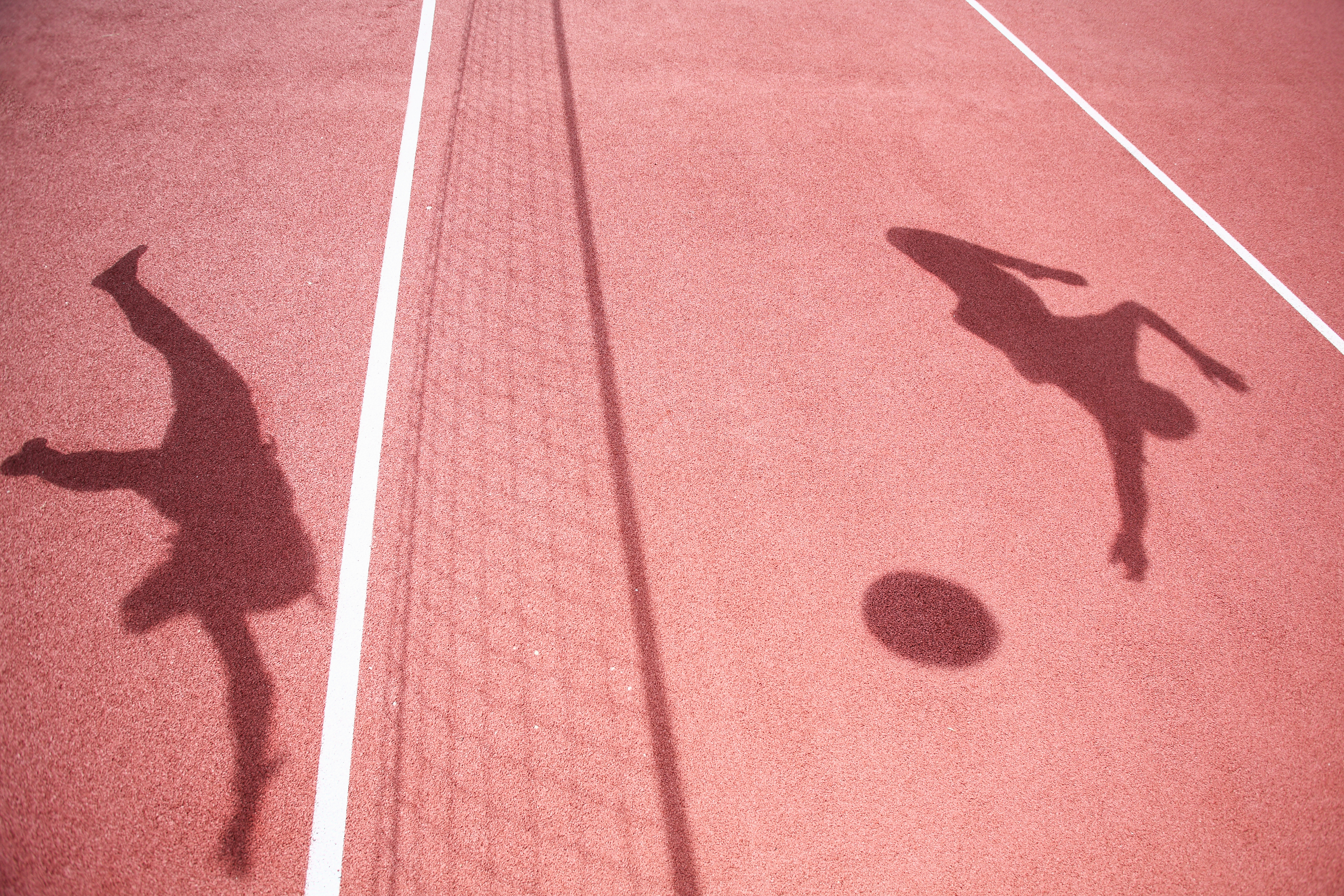 The image shows the shadows of two people playing soccer on a field, with one kicking the ball and the other running. The image is used in a Rewind article