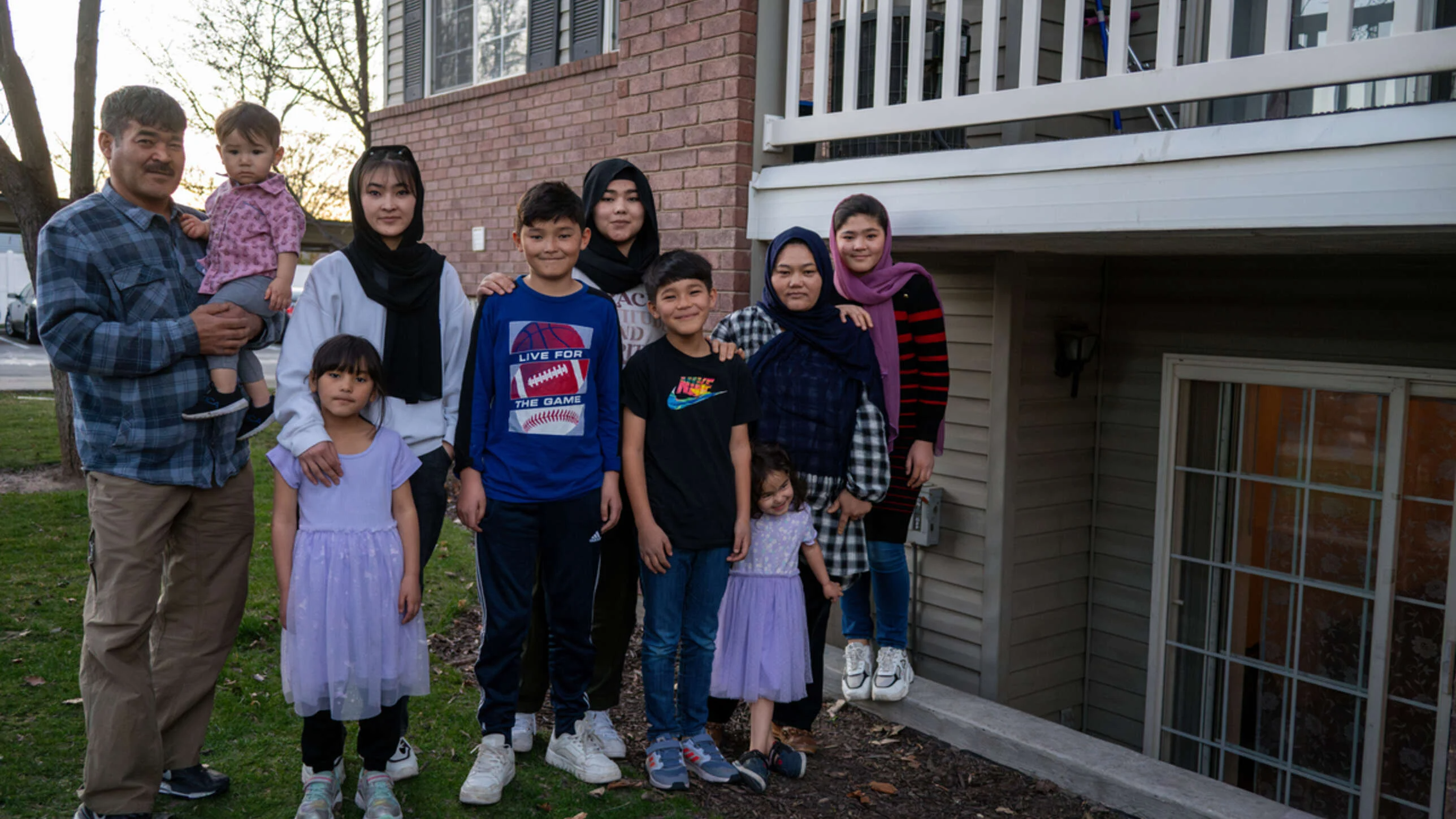 A family of 10 poses together outside a house