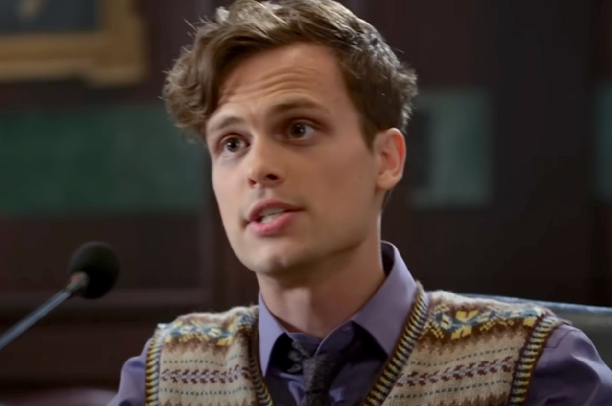 Matthew Gray Gubler, wearing a patterned sweater vest over a collared shirt and tie, speaks into a microphone as Spencer Ried on Criminal Minds