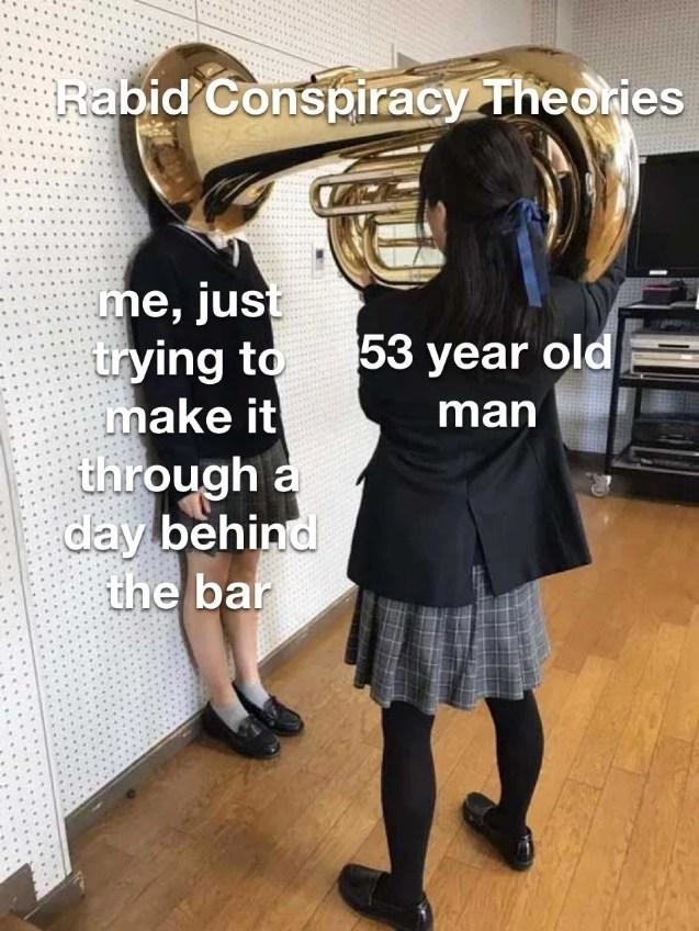 A meme with one student holding a tuba over another's head. Text reads: "Rabid Conspiracy Theories", "me, just trying to make it through a day behind the bar", "53 year old man"