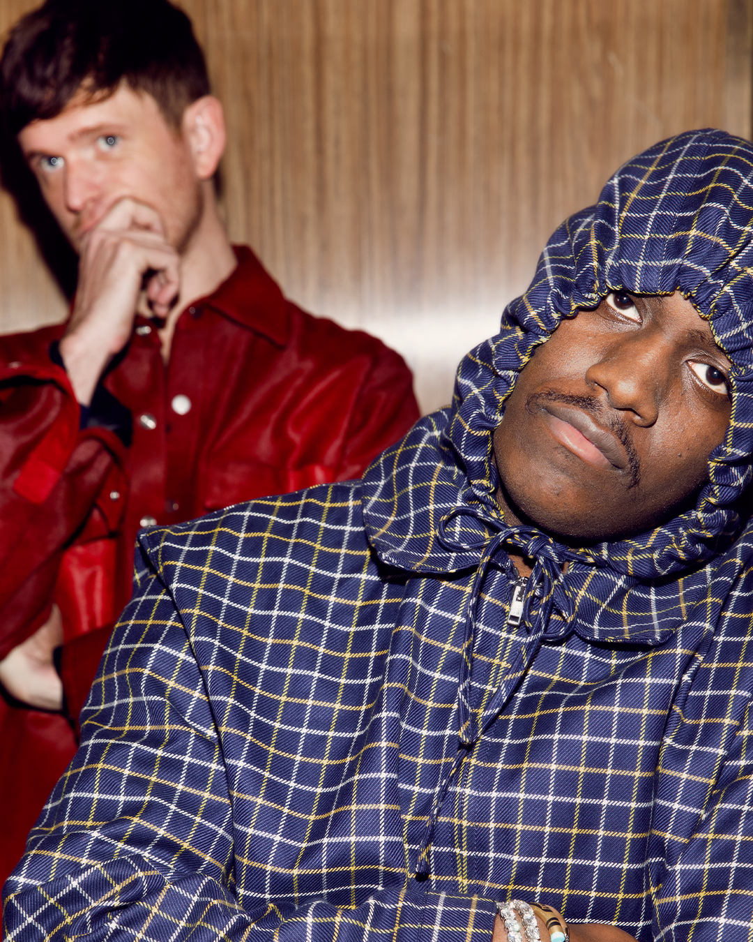 James Blake in a red shirt and Lil Yachty in a hooded checkered jacket pose for a photo