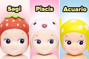 Tres muñecos con cascos: uno de fresas etiquetado "Sagi", otro de conejo etiquetado "Piscis" y otro de estrellas etiquetado "Acuario"