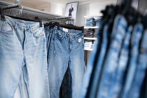 Row of jeans on hangers in a clothing store with a blurred framed picture of a person in the background