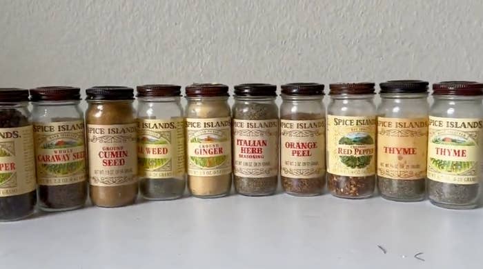 A lineup of nine Spice Islands spice jars, including Caraway Seed, Ground Cumin Seed, Dill Weed, Ground Ginger, Italian Herb Seasoning, Orange Peel, Red Pepper, Thyme, and Thyme