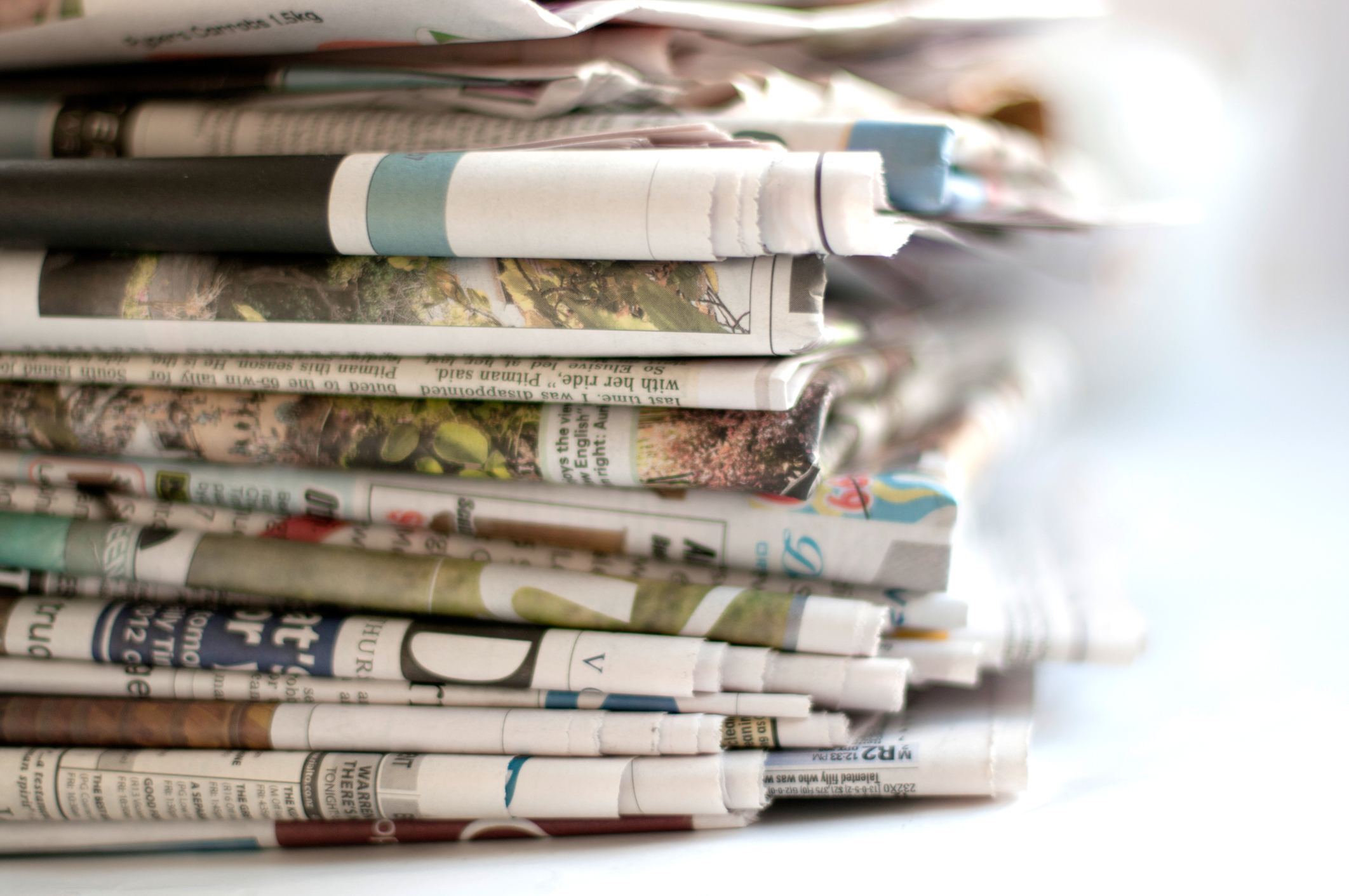 A close-up of a stack of folded newspapers, possibly indicating a collection of recent or significant headlines. No text visible