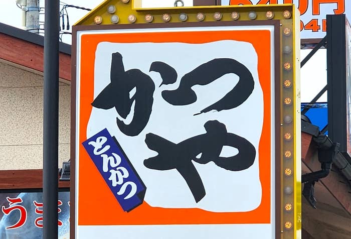 とんかつ屋の看板。「かつや」と大きく書かれ、横に「とんかつ」と記載。