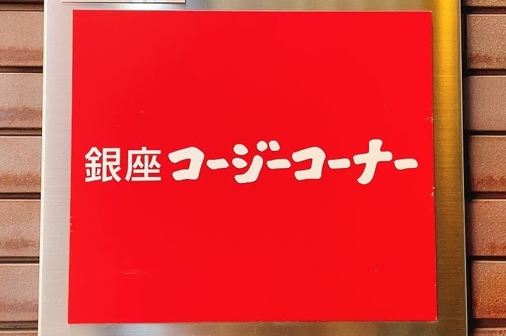 Sign with Japanese characters on a red background, mounted on a brick wall