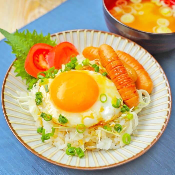 目玉焼き、ソーセージ、ご飯、千切りキャベツ、トマト、味噌汁が添えられた和朝食。