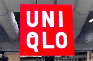 Uniqlo store sign hanging from ceiling with clothing displays underneath