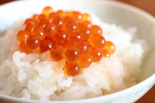 ご飯の上にいくらが乗った料理の近接画像。