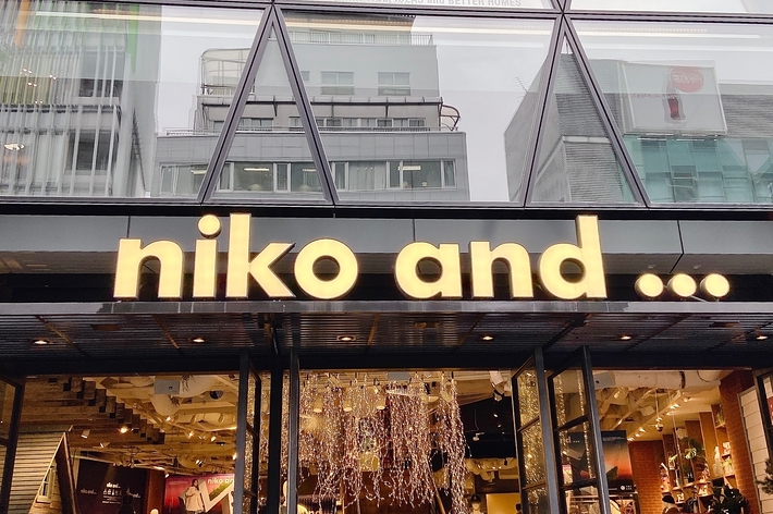 ショッピング店「niko and …」の店頭。テキスタイルや家具が飾られており、ガラス張りの外観が特徴的。