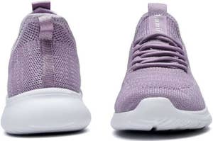 Front and side view of purple athletic sneakers with icons below showing the shoes are suitable for walking, working, shopping, traveling, working out, fitness, gym, and sports