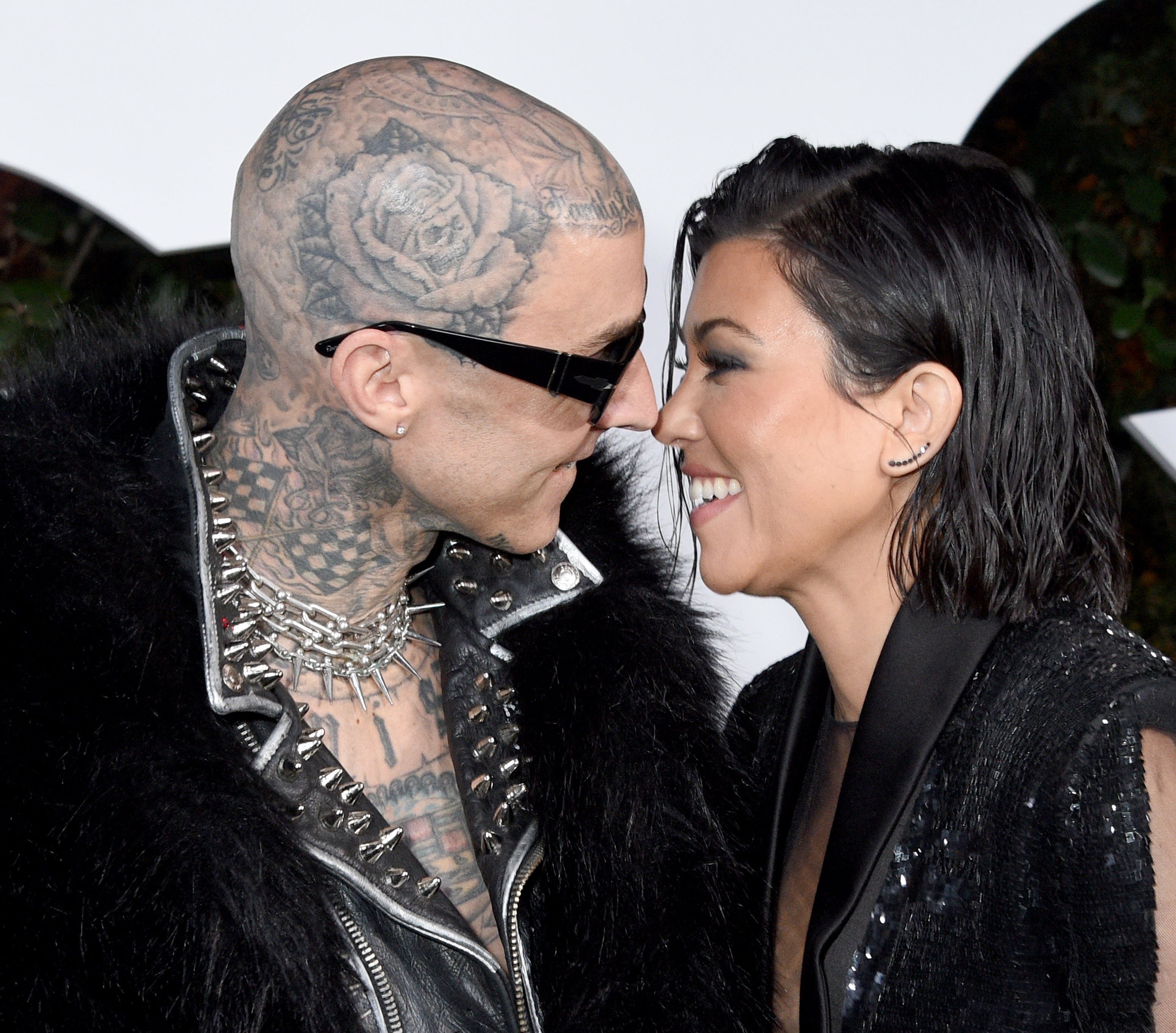 Travis Barker and Kourtney Kardashian smiling and touching noses at an event