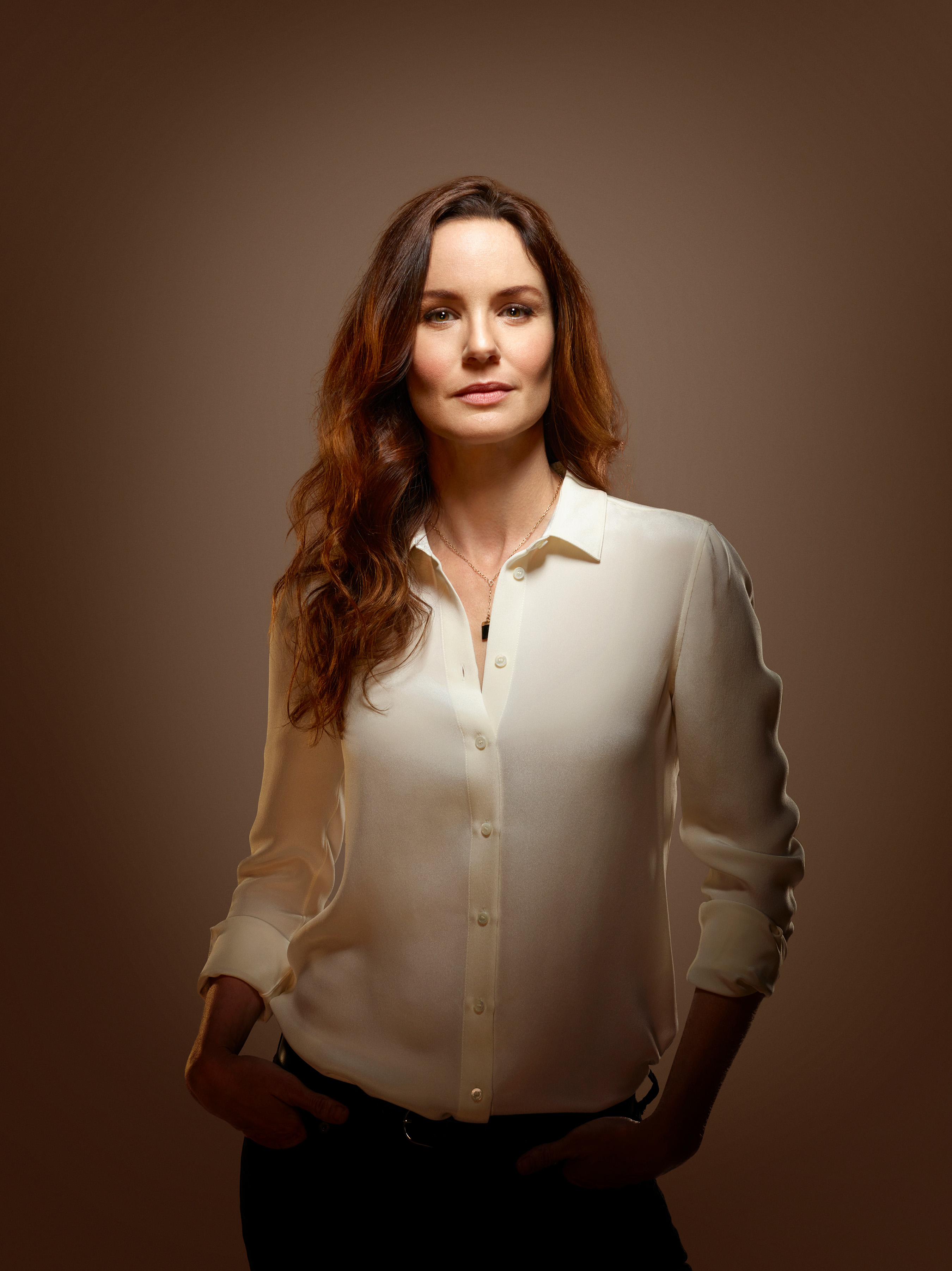 Sarah Wayne Callies poses confidently in a button-up blouse with hands in pockets