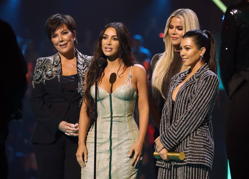 Kris Jenner, Kim Kardashian, Khloe Kardashian và Kourtney Kardashian trên sân khấu tại một sự kiện, với Kim phát biểu trước micro
