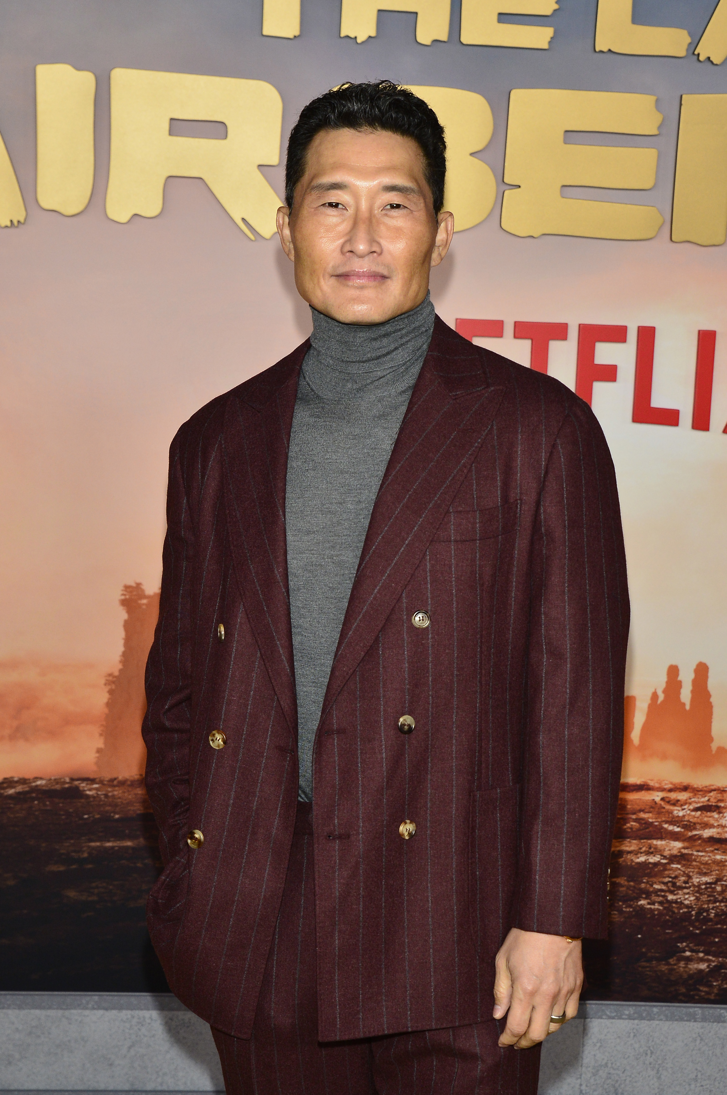 Daniel Dae Kim on the red carpet in a dark pinstripe suit and turtle neck at the Netflix event for The Last Airbender