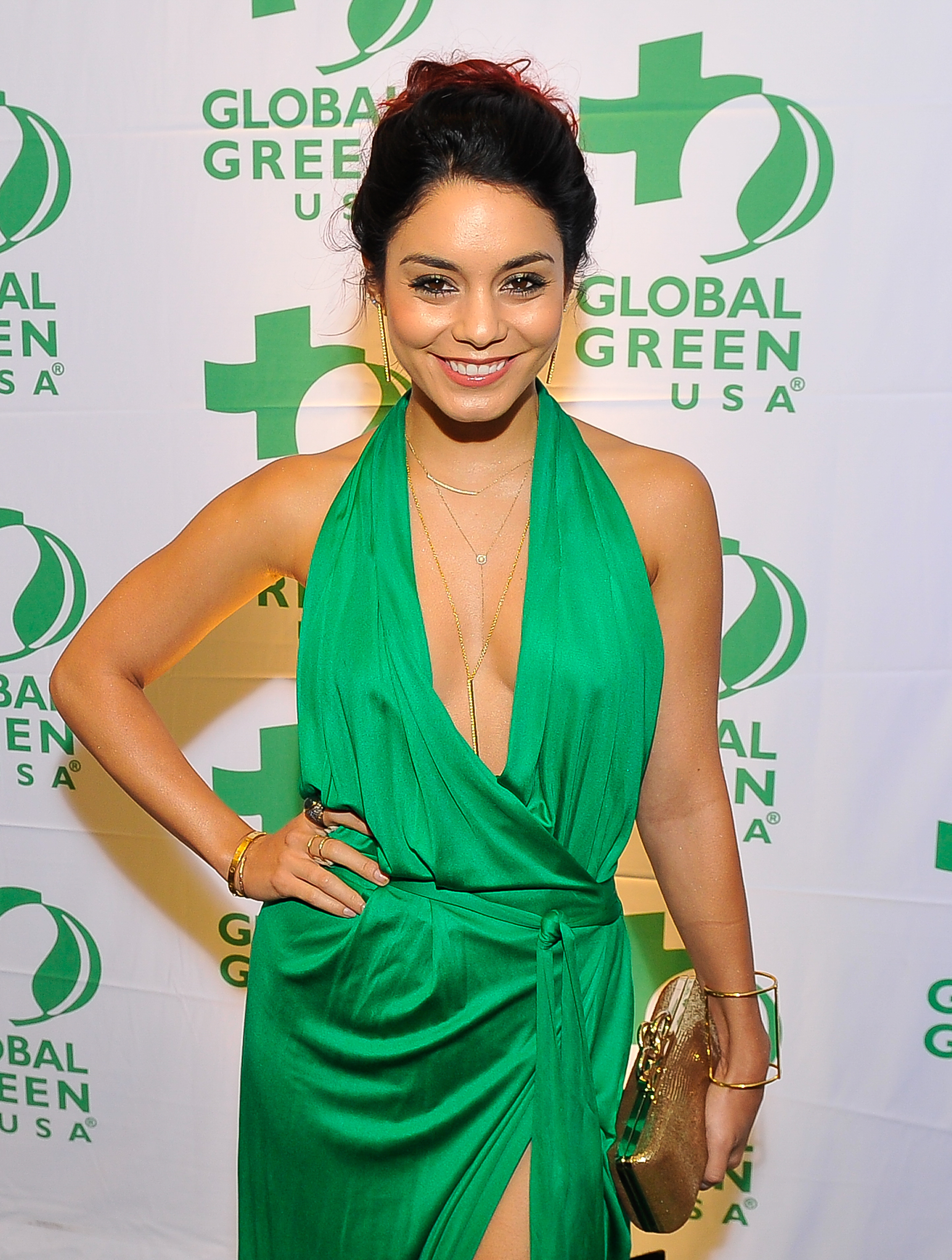 Vanessa Hudgens poses at the Global Green USA event, wearing a sleeveless, deep V-neck green gown with a thigh-high slit, holding a gold clutch