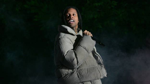 A$AP Rocky performs on stage wearing a puffy jacket, holding a microphone, with a smoky backdrop