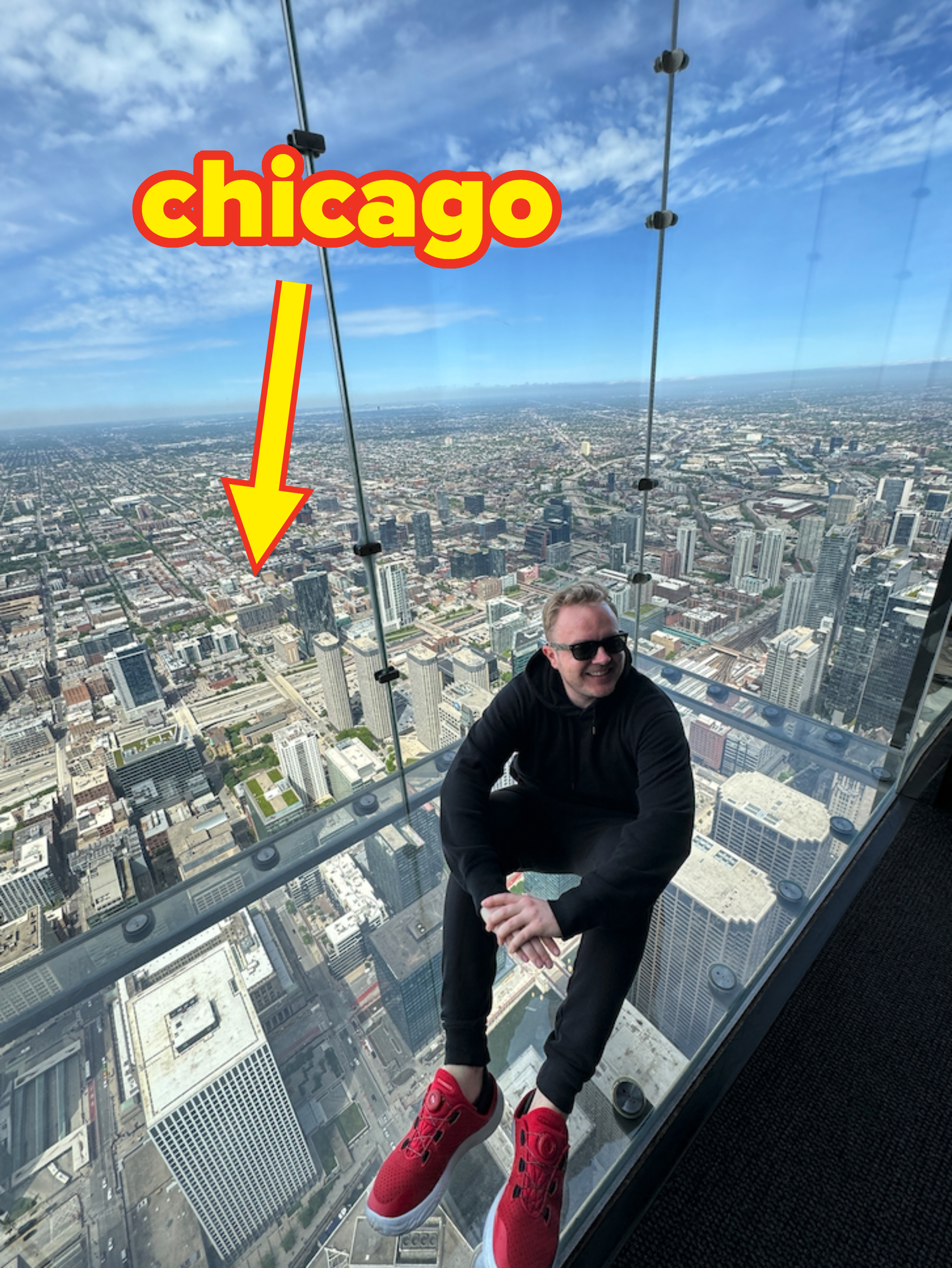 Person sitting on glass floor high above city landscape