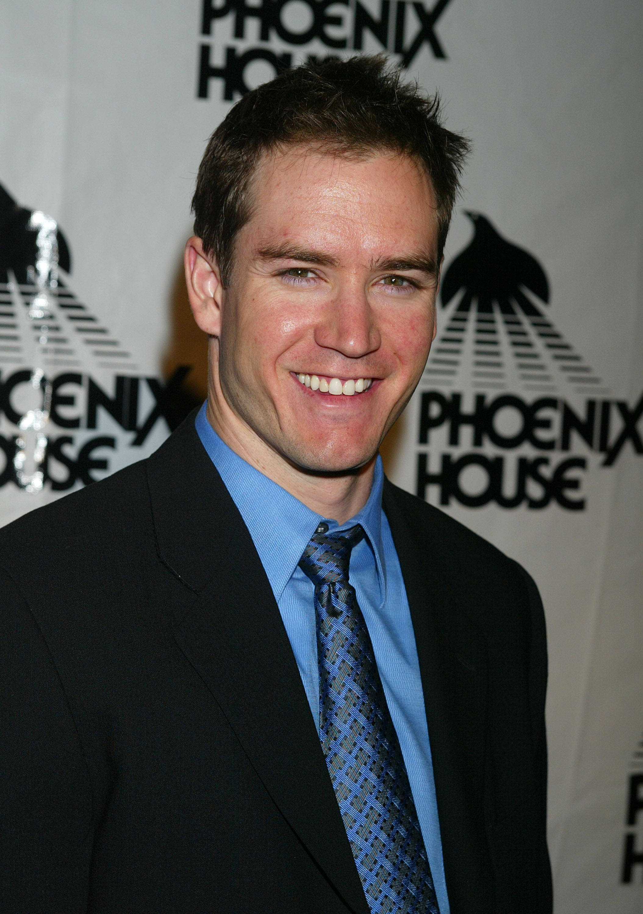 A man in a suit and tie smiles for the camera at the Phoenix House event