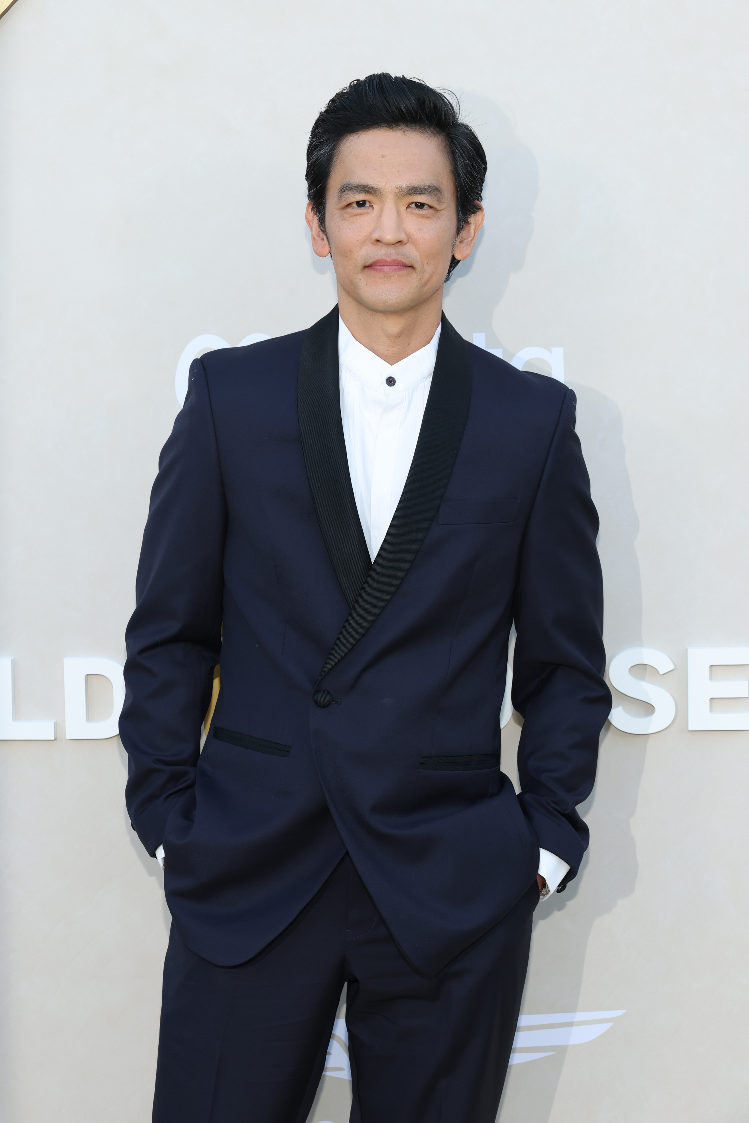 John Cho poses in a suit with a white shirt at a formal event