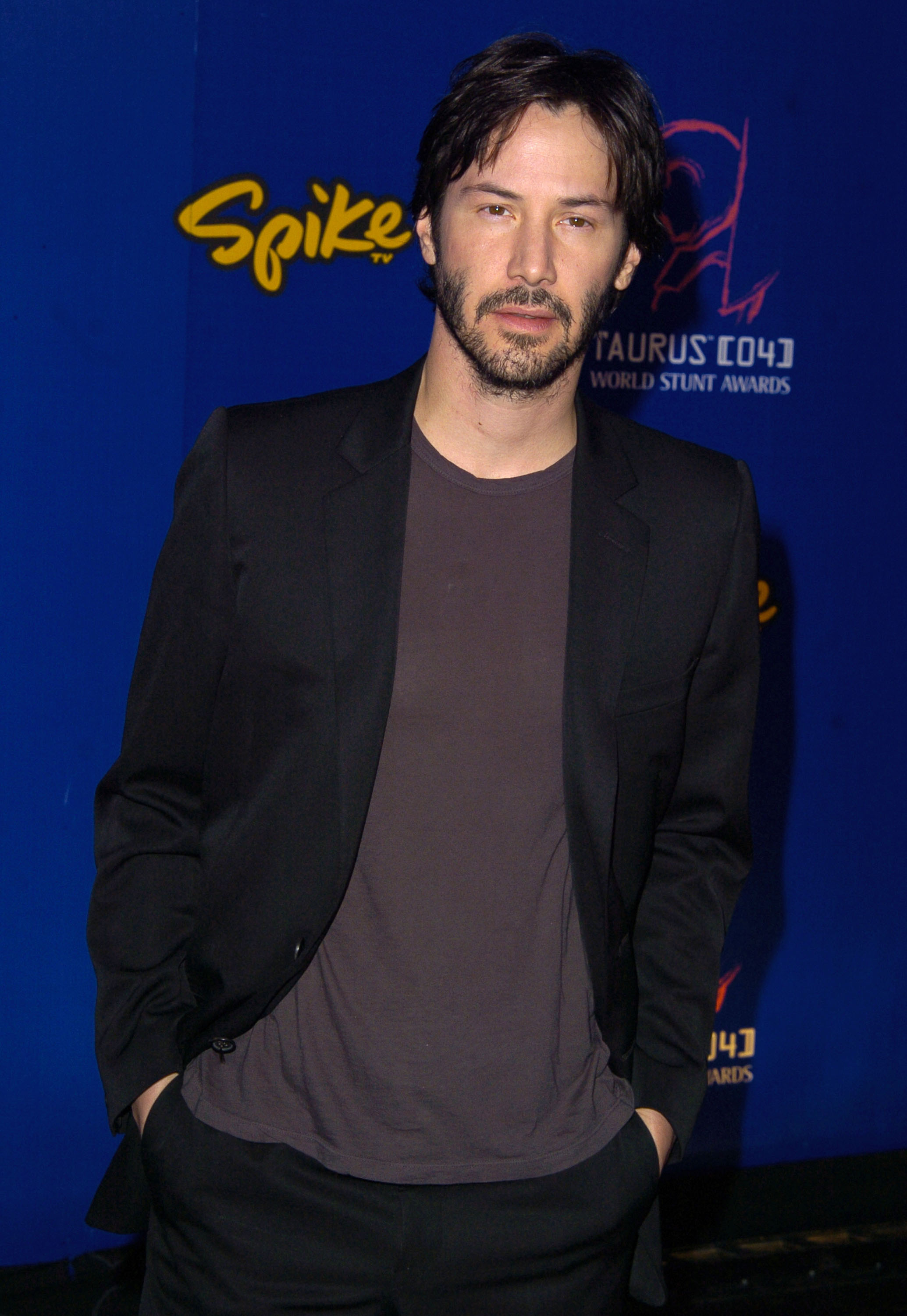 Keanu Reeves at the 2004 Taurus World Stunt Awards, wearing a casual dark blazer over a t-shirt with his hands in his pockets