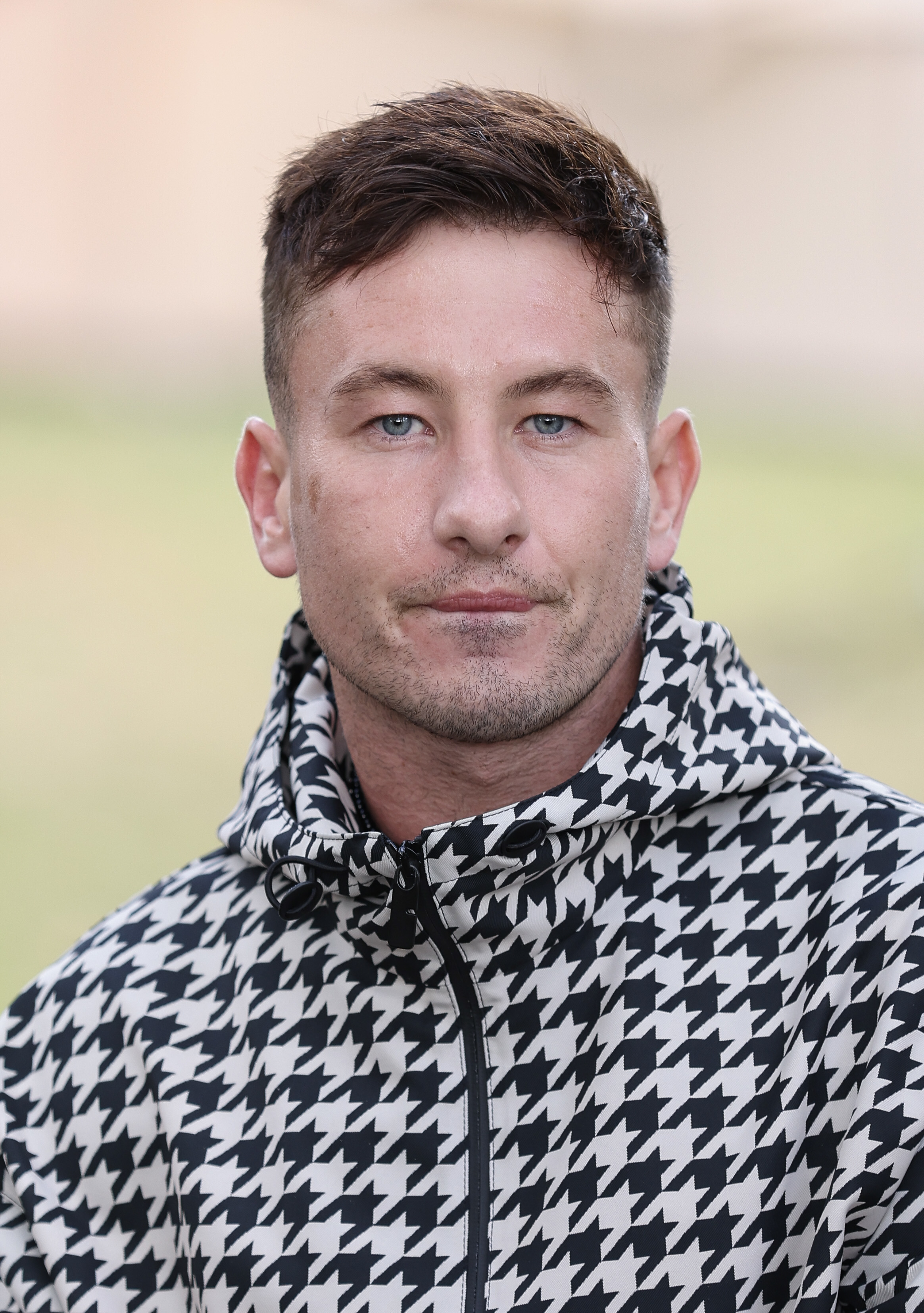 Barry Keoghan in a houndstooth patterned jacket, outdoors, posing with a neutral expression