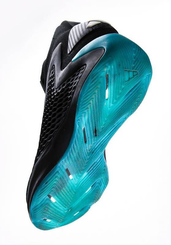 Photograph of an athletic shoe being held upside down, showcasing the unique patterned tread and textured sole design