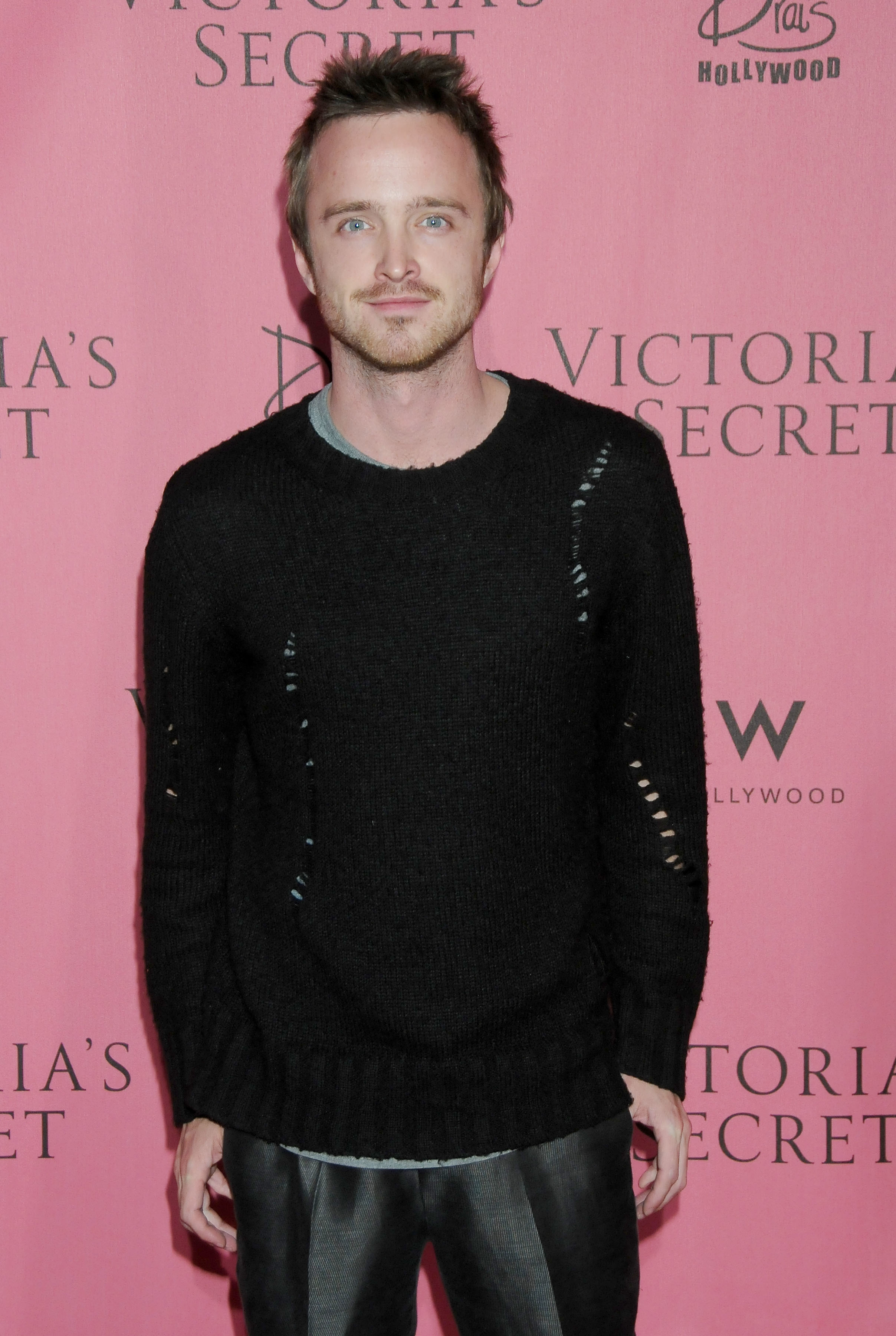 Aaron Paul poses in a ripped sweater on the red carpet at a Victoria's Secret event