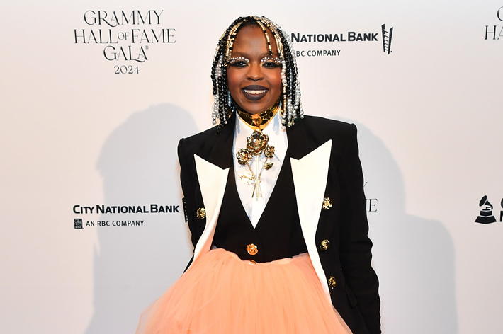 Lauryn Hill at the 2024 Grammy Hall of Fame Gala wearing a black blazer with white lapels, gold jewelry, and a voluminous peach-colored skirt