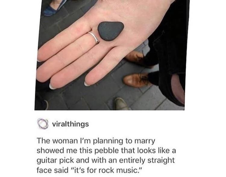 A person's hand holding a pebble shaped like a guitar pick. Text reads: "The woman I'm planning to marry showed me this pebble that looks like a guitar pick and with an entirely straight face said 'it's for rock music.'"