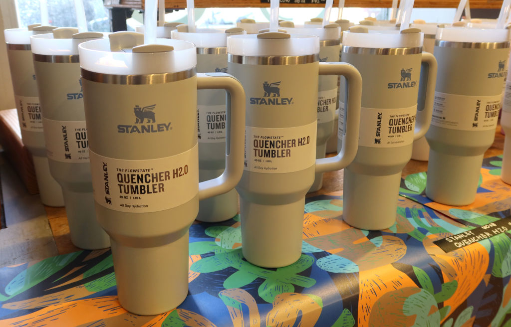 Several Stanley Quencher H2.0 Tumblers are displayed on a table with a floral-patterned tablecloth
