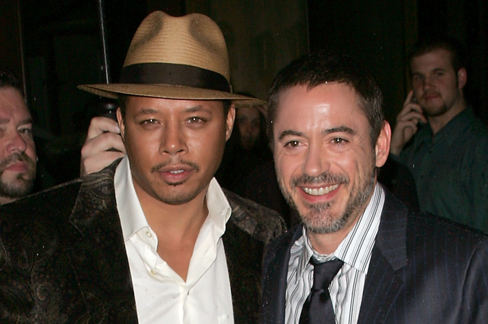 Terrence Howard in a fedora and Robert Downey Jr. in a suit and tie, standing together at a public event