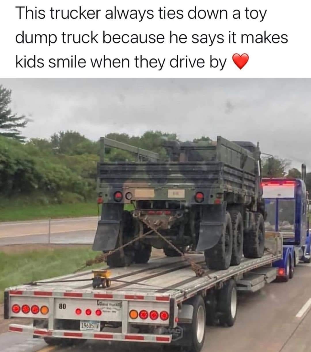 A trucker secures a toy dump truck to his flatbed trailer, stating it makes kids smile when they drive by