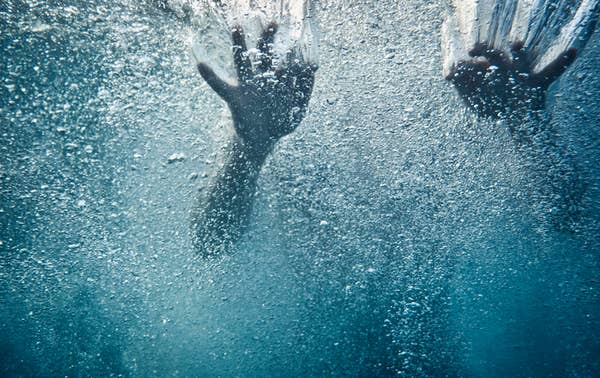 Underwater view of hands reaching through bubbles and water