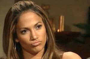Jennifer Lopez making an expressive face and pouting while seated during an interview