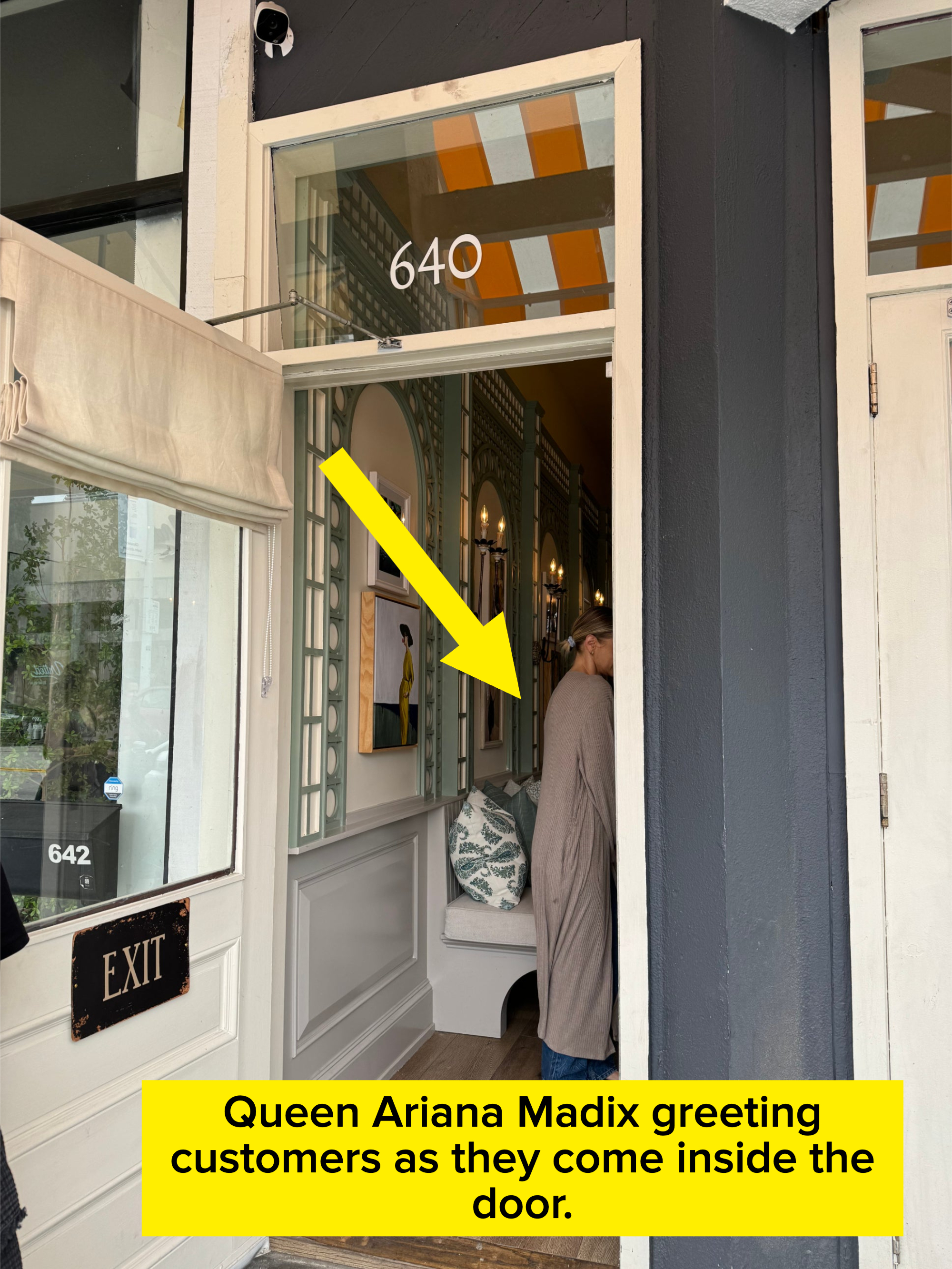 A person wearing a long, flowing garment stands inside the entrance of a building with the address 640. The entrance has a partially open door with &quot;EXIT&quot; on it