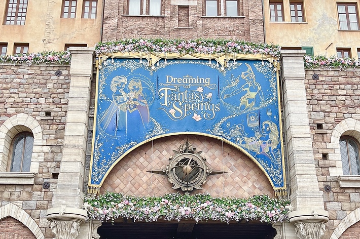 建物の入り口に「Dreaming at Fantasy Springs」と書かれた大きな看板が掲げられている。看板にはファンタジー風のイラストが描かれている。