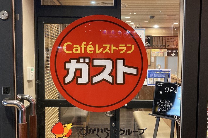 ガラス扉に取り付けられた「Cafeスマイル カスタ」というテキストの赤い看板。