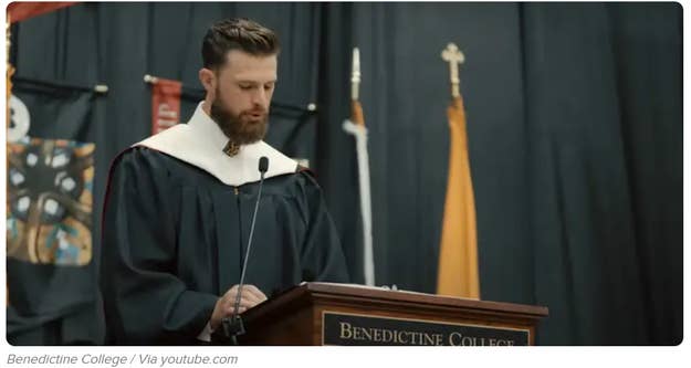 卒業式でベネディクティン大学のポディウムに立ってスピーチをしている男性。