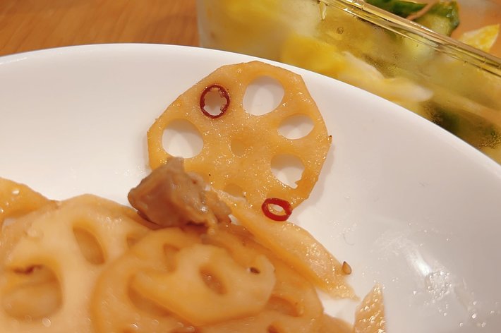 白い皿に盛られたレンコンの炒め物と、ガラス容器に入った黄色と緑色の漬物が写っています。