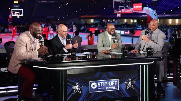 From left to right: Shaquille O'Neal, Ernie Johnson, Kenny Smith, and Charles Barkley are seated at a desk, holding microphones during a live sports broadcast