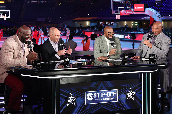 Shaquille O'Neal, Ernie Johnson, Kenny Smith, and Charles Barkley are discussing basketball at the "TNT Tip-Off" set, with a basketball court in the background