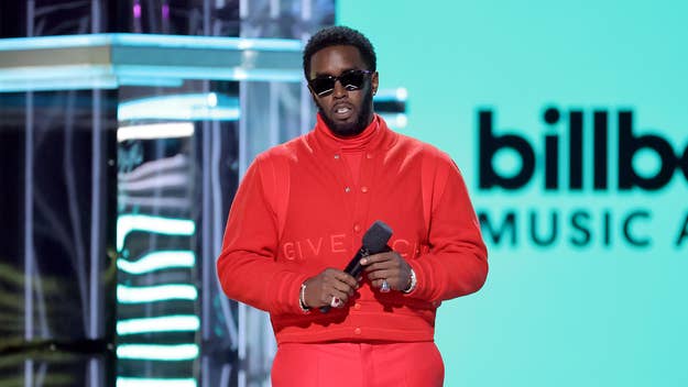 Sean "Diddy" Combs on stage at the Billboard Music Awards, holding a microphone, wearing a monochrome outfit with a jacket and trousers
