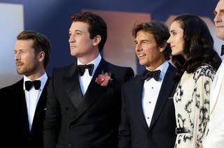 Glen Powell, Miles Teller, Tom Cruise, Jennifer Connelly, and Jon Hamm stand together on the red carpet, dressed in formal attire