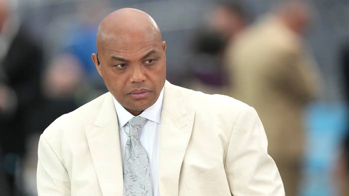 Charles Barkley in a white suit with a light patterned tie, looking off-camera